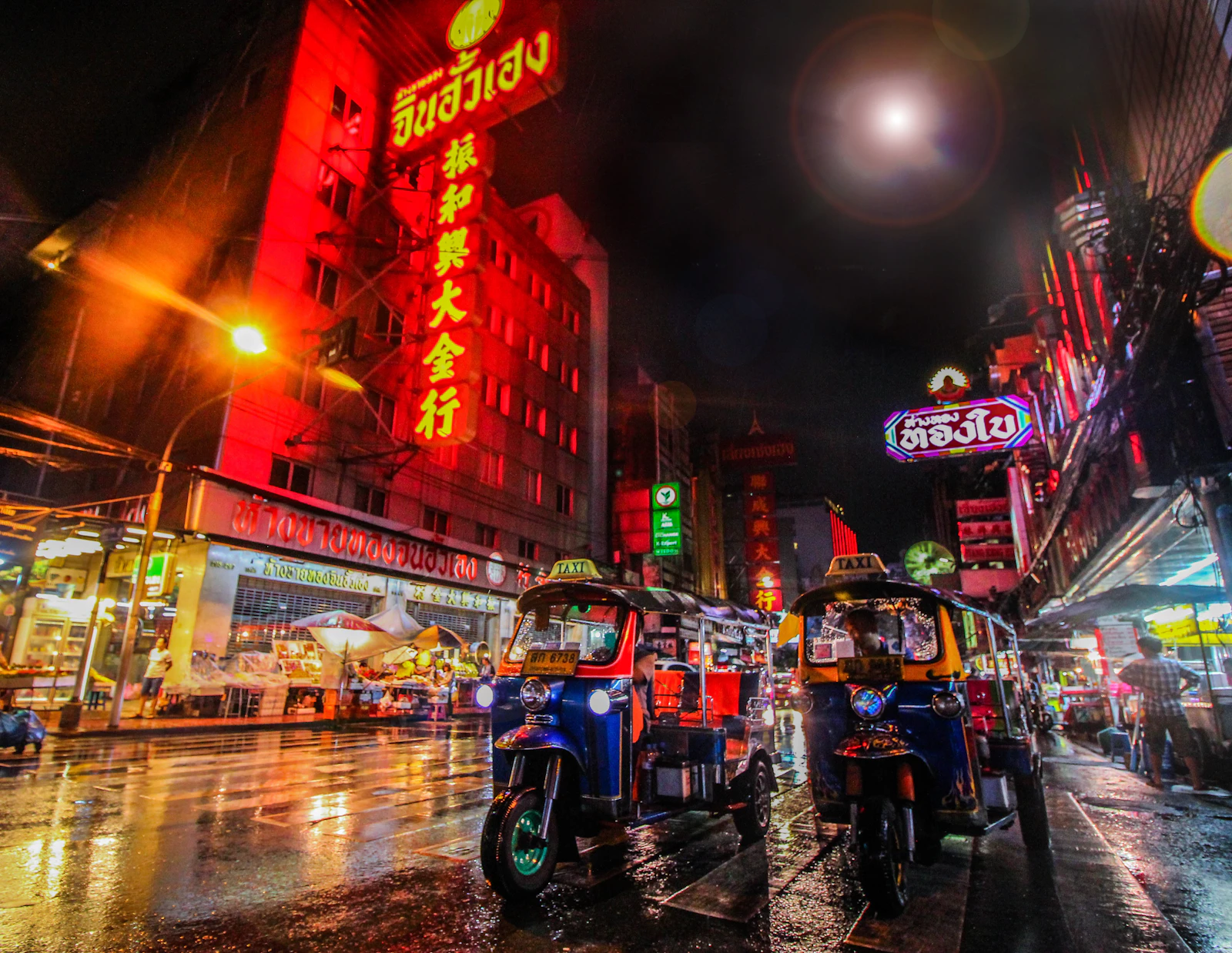 Tuk-tuks on a neon-lit street in Bangkok at night